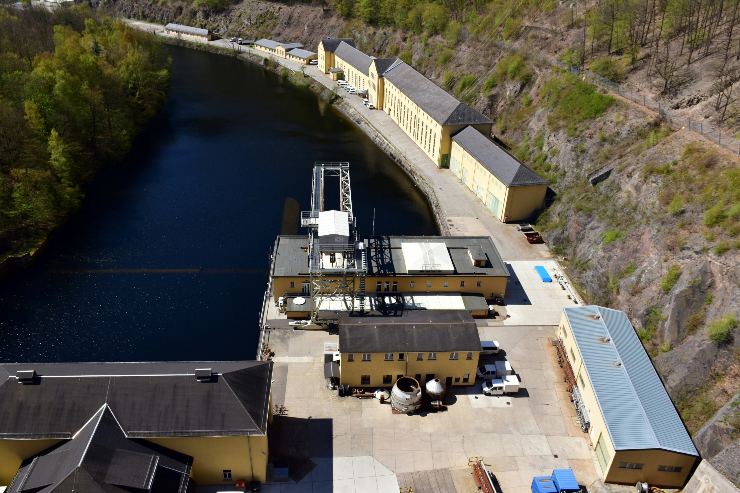 an aerial view of a factory next to a body of water